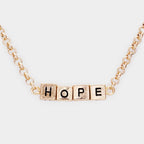 Worn gold HOPE cube pendant necklace by Madeline Love in the Hope Monroe Closet